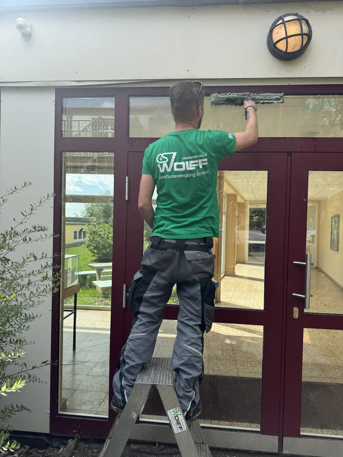 Glasreinigung an einer Glastuer durch einen Mitarbeiter der C&S Wolff GmbH